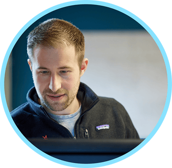 Man looking down at a computer monitor within a circle with a light blue border